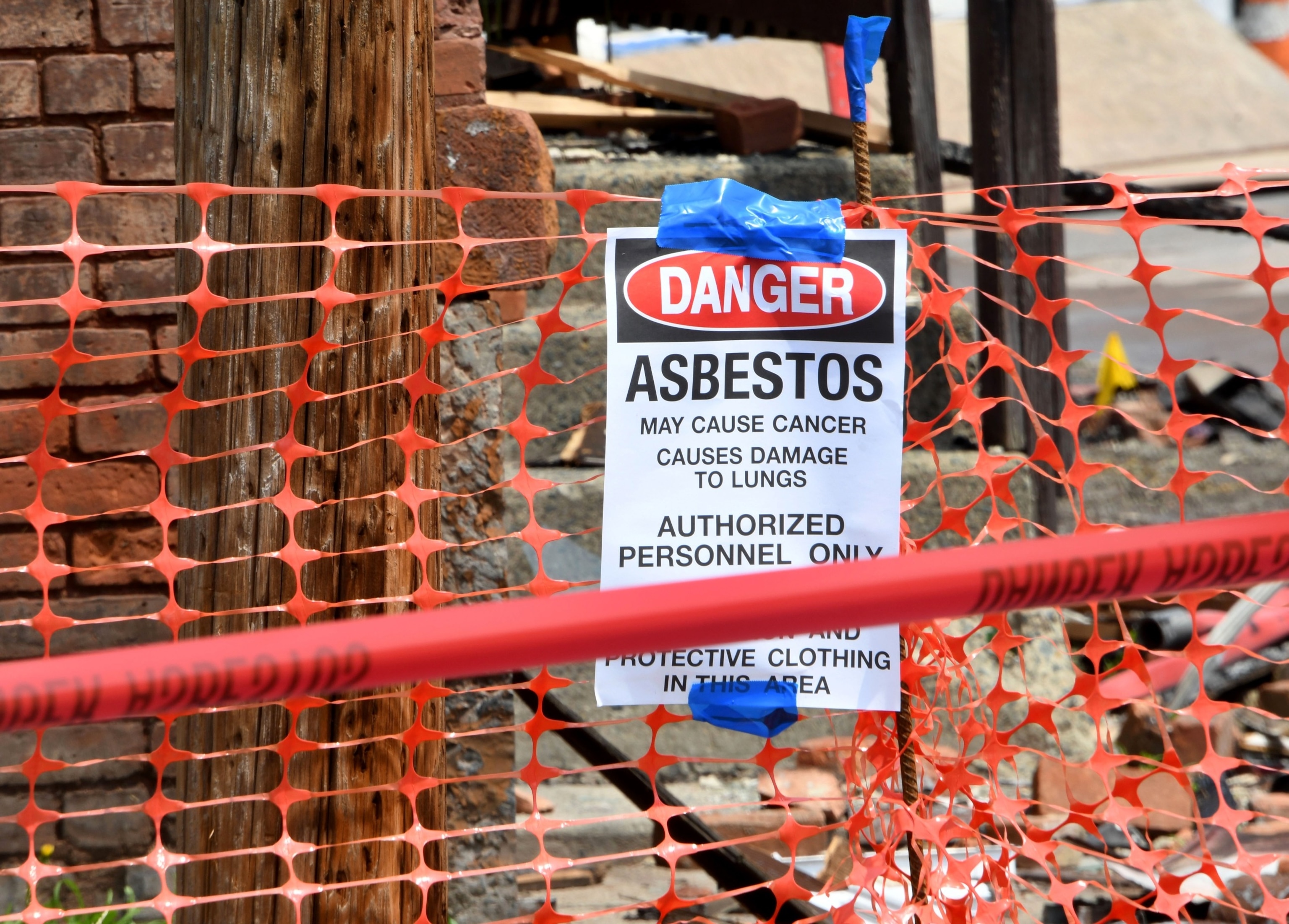 PHOTO: An asbestos danger sign is seen in front of the three row houses that were heavily damaged by fire, July 6, 2021 in Watervliet, N.Y.