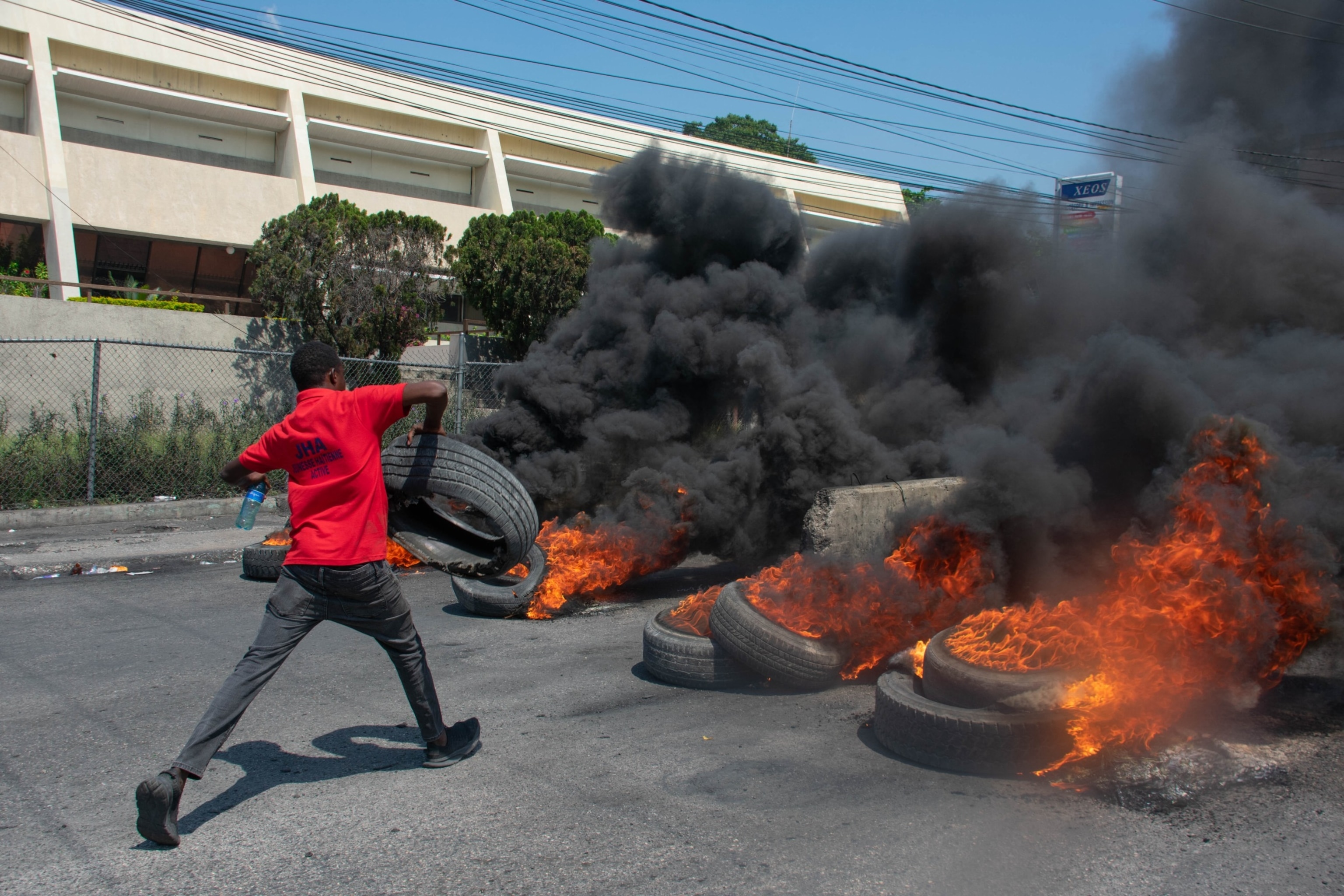 A protester burns tires during a demonstration following the resignation of its Prime Minister Ariel Henry, in Port-au-Prince, Haiti, on March 12, 2024.(Photo by Clarens SIFFROY / AFP) (Photo by CLARENS SIFFROY/AFP via Getty Images)