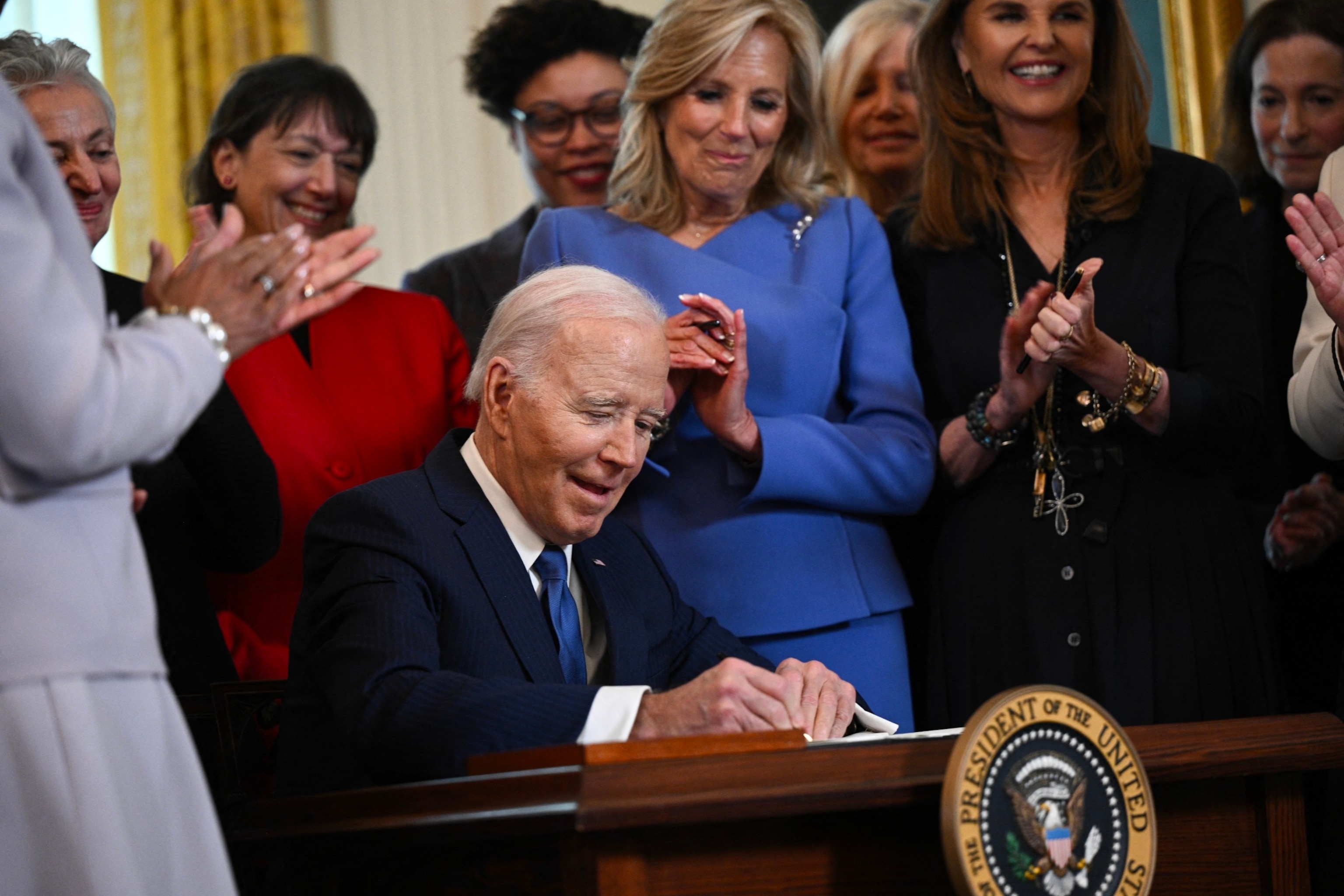 PHOTO: President Joe Biden signs an executive order aimed at advancing the study of women's health during a reception honoring Women's History Month in the East Room of the White House in Washington, DC, March 18, 2024.